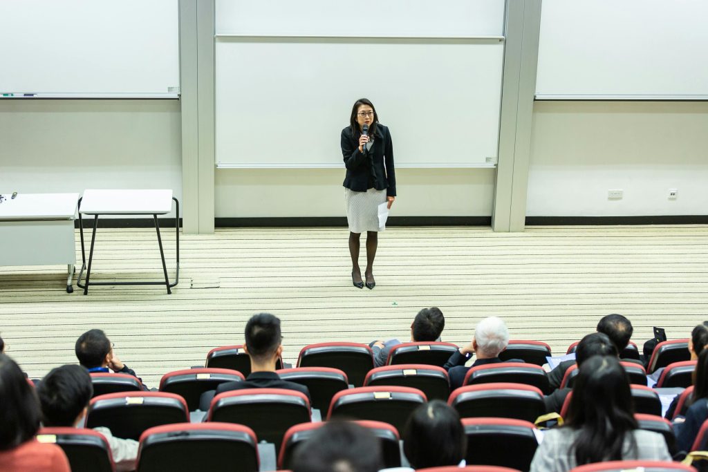 Woman Holding Microphone Standing in Front of Crowd